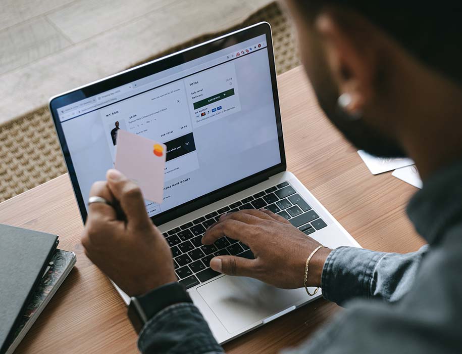 Man holding MasterCard and making purchase on laptop.